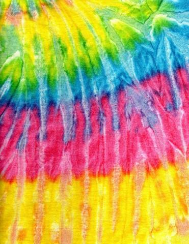 a close up image of tie dyed fabric, with yellow at the top and turning into green, blue, red and yellow again