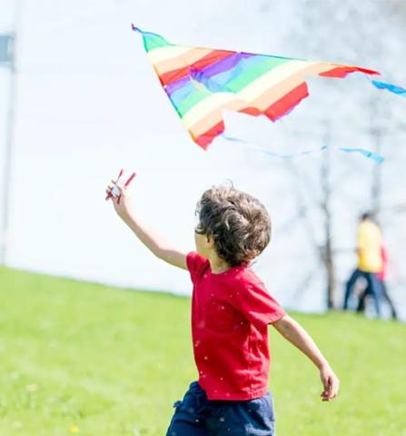 a child flying a colorful striped kite outside