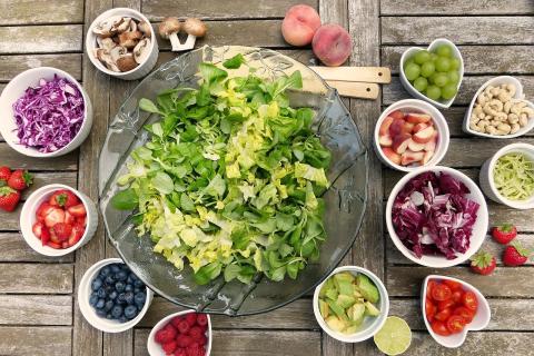 an image of one large bowl full of shredded lettuce surrounded by smaller bowls with different salad vegetables in them