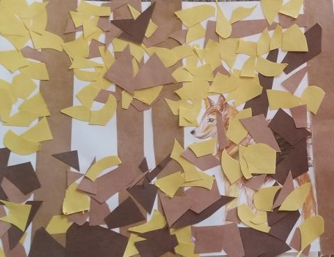 A photograph of an artwork of a construction paper collage of a wolf hiding amongst a trees