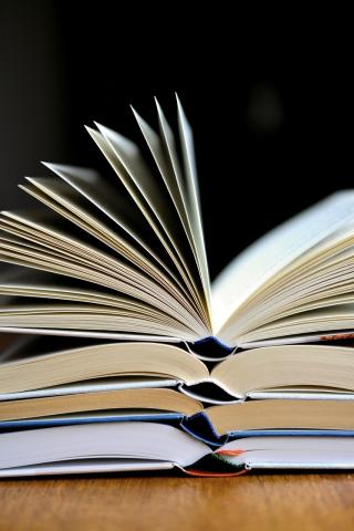 a stack of four open books against a black background