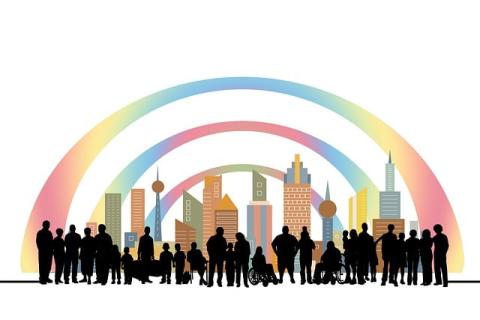 A long line of black silhouetted people of all shapes and sizes, including some wheelchair users, stands in front of a skyline and three arcs above them displaying a rainbow spectrum of colors..