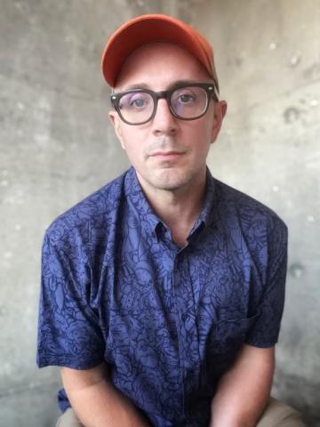 Headshot of Steve Burns in blue shirt and red hat