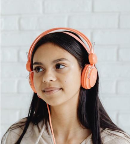 Close up photo of a light-brown skinned girl with long hair wearing headphones