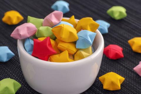 multi-colored paper stars in a white cup against a black background