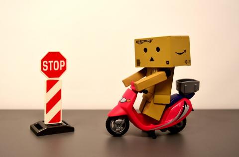 a small cardboard figure on a red scooter next to a stop sign