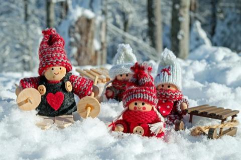 Photo of a snow scene with wooden dolls in winter-themed sweaters and a tiny sled