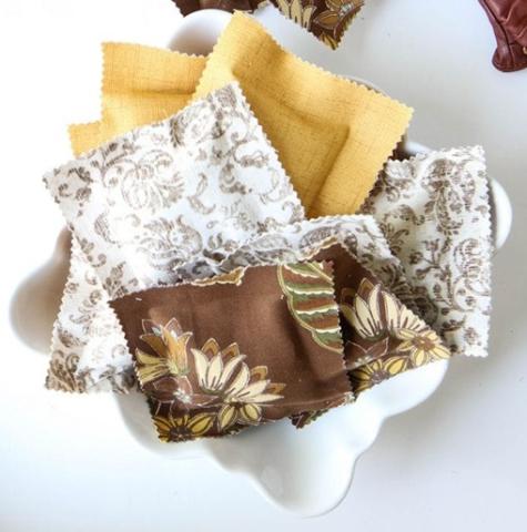 a pile of fabric squares in browns, yellows and whites in a white dish