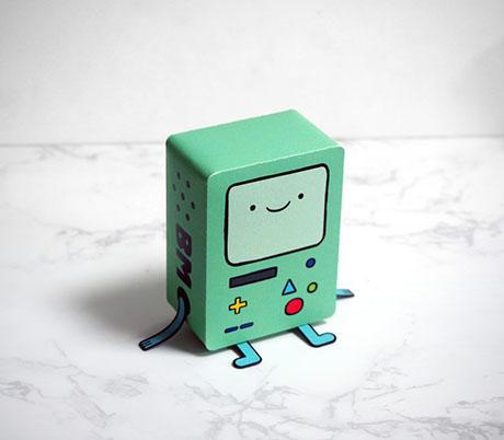 a small green robot with a smiling face sits on a white marble countertop