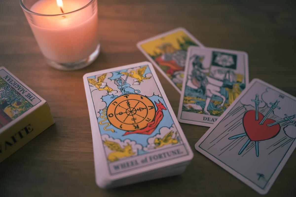 four tarot cards are laid out on a table in front of a white candle