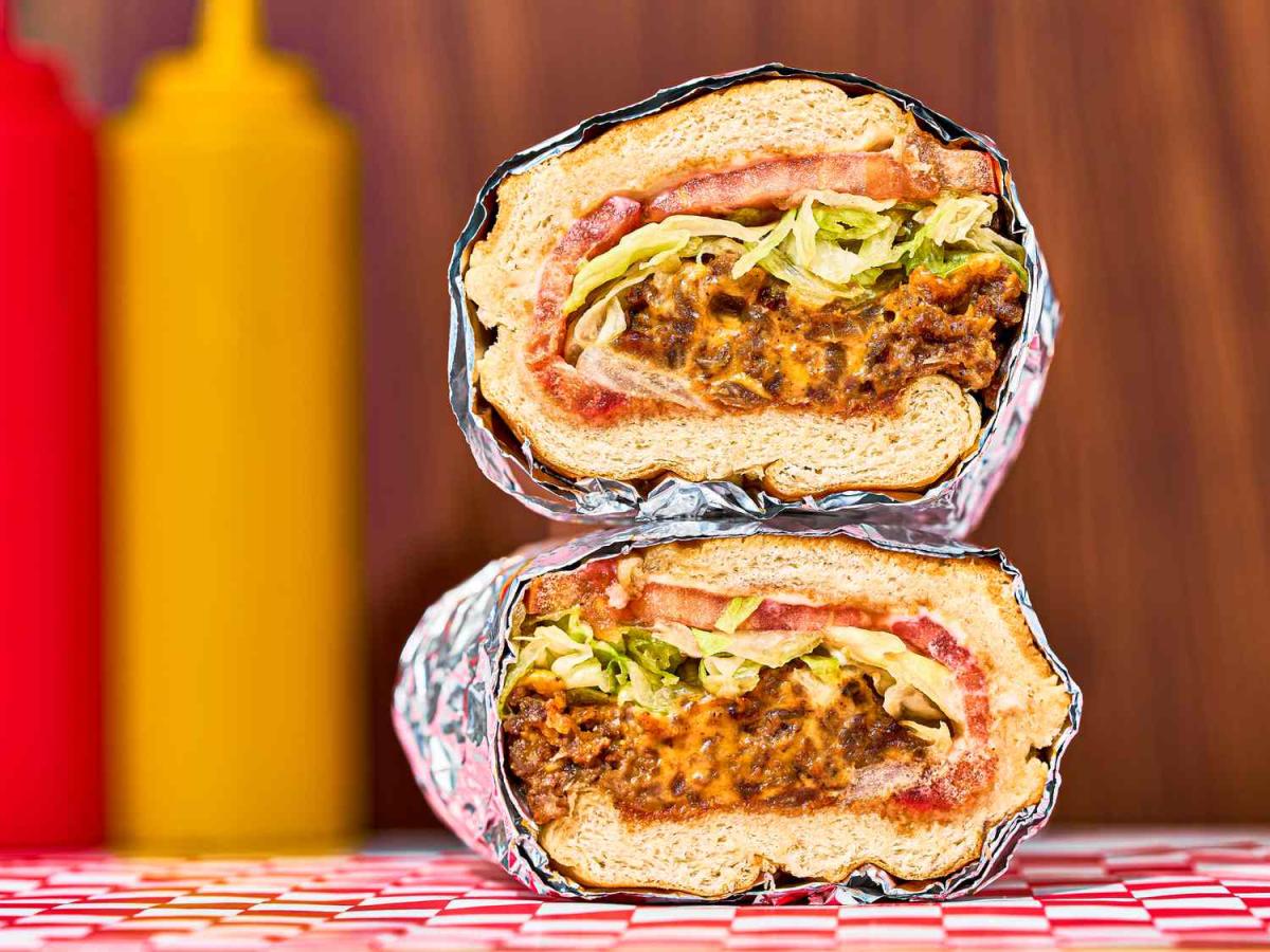 two halves of a meat sandwich wrapped in foil and stacked on top of each other