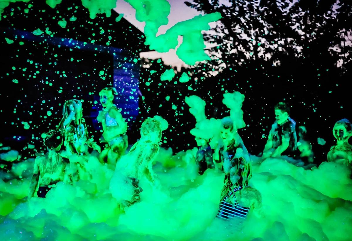 Photo of people jumping around in glowing green foam.
