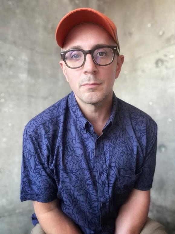 Headshot of Steve Burns in blue shirt and red hat