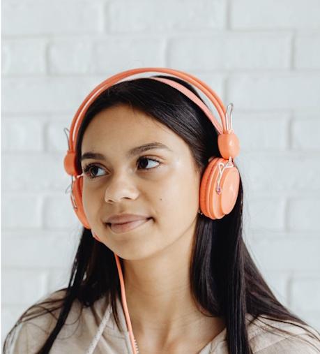 Close up photo of a light-brown skinned girl with long hair wearing headphones