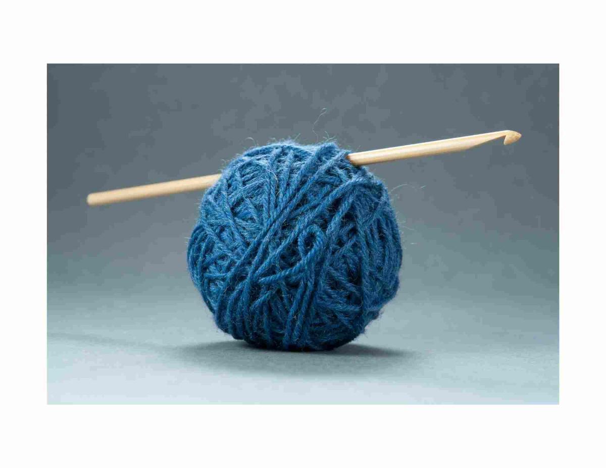 Ball of dark blue yarn with a wooden crochet hook.